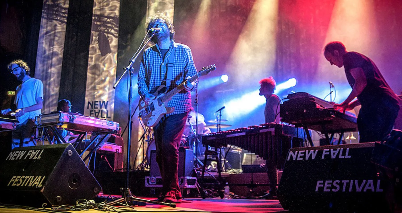Et band på scenen under New Fall Festival, omgitt av lilla og blå scenelys.