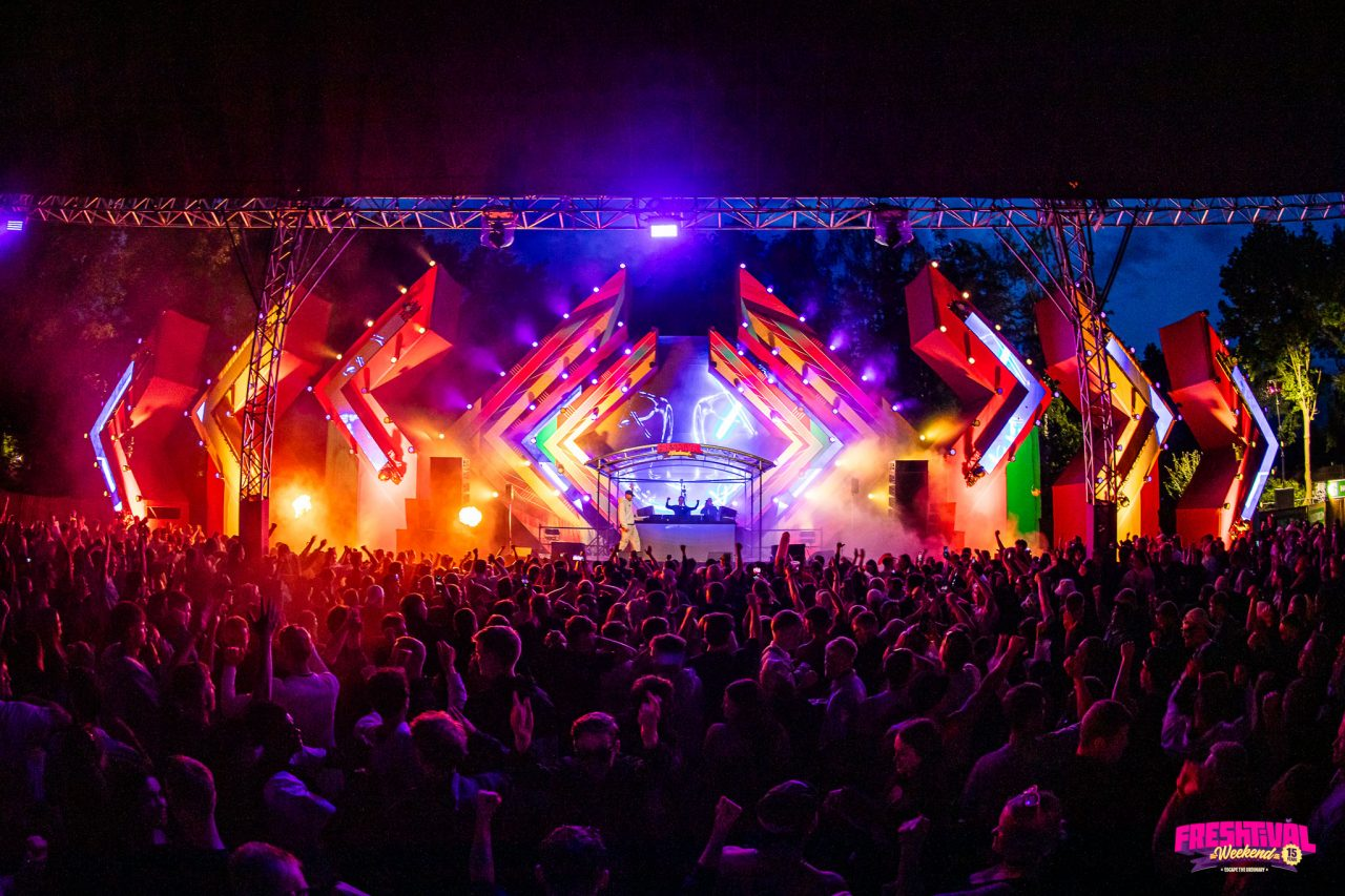 Freshtival med scene, fargerike lys og publikum om kvelden